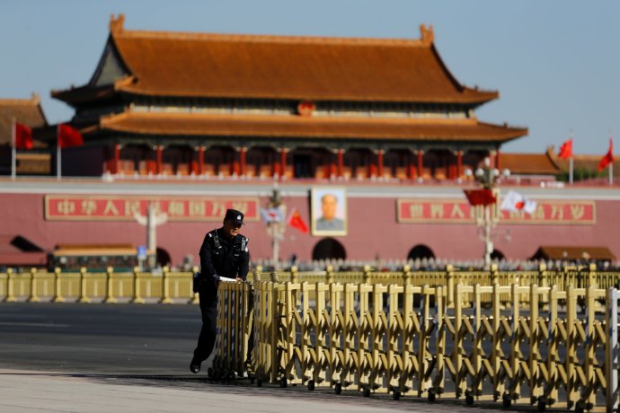 Čínský policista sklízí bezpečnostní zábrany na pekingském náměstí Nebeského klidu (Tchien-an-men), říjen 2018. Foto: Thomas Peter, Reuters
