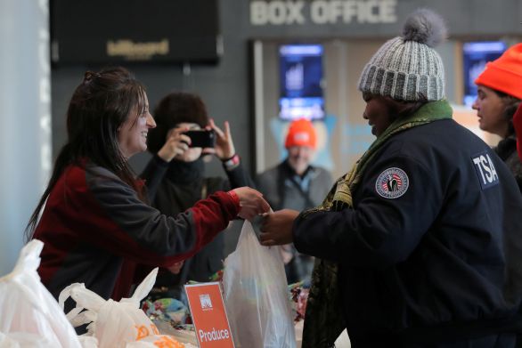 Dobrovolnice předává v New Yorku vládní zaměstnankyni Agentury pro dopravní ochranu (TSA) tašku s jídlem a dalšími potřebami, aby jí pomohla ve složité finanční situaci. Kvůli shutdownu nedostávají vládní pracovníci už 33. den plat. Foto: Brendan McDermid, Reuters