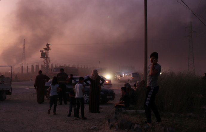 Lidé zpovzdálí sledují zkázu arabsko-kurdského města Ras al- Ajn na syrsko-tureckých hranicích, ze kterého utekli před tureckou invazí. Foto: Rodi Saíd, Reuters