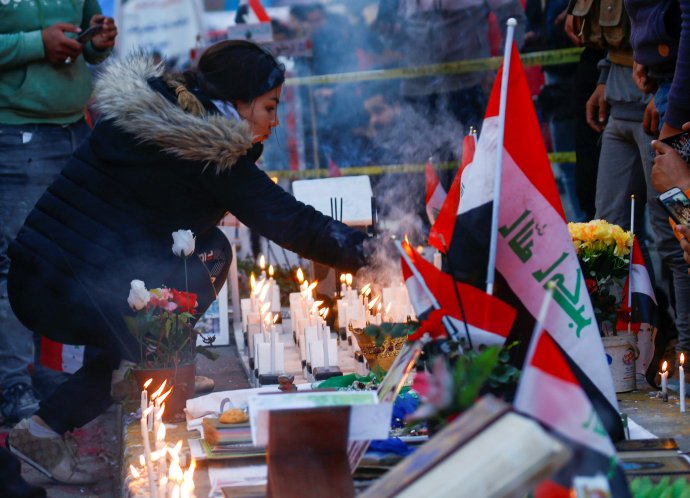 Irácká demonstrantka zapaluje v iráckém Bagdádu svíčku za lidi zabité během protivládních protestů. Foto: Alá al-Mardžání, Reuters