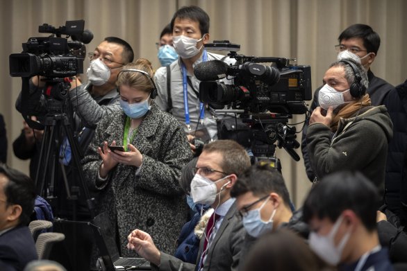 Novináři s nezbytnými rouškami, které je před ničím nechrání, na tiskové konferenci Informační kanceláře Státní rady v Pekingu. Foto: AP, ČTK