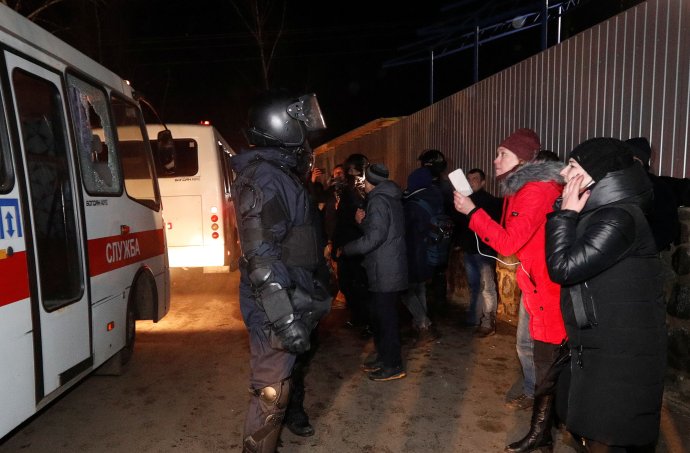 Policista a Ukrajinci protestující proti příjezdu jejich spoluobčanů z čínského Wu-chanu zasaženého epidemií koronaviru 2019-nCoV. Sanatorium v obci Novi Sanžary. Foto: Valentyn Ogirenko, Reuters