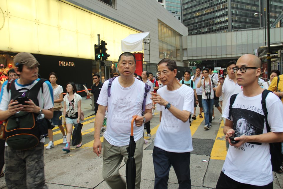 Jimmy Lai (v bílém vlevo) na demonstraci k výročí předání Hongkongu Číně (1. července 2013). Foto: Voice of America, Wikimedia Commons