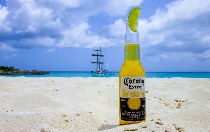 Lahev piva Corona na mořské pláži. Foto: Pxhere