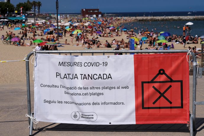 Barcelonská pláž plná lidí a cedule říkající "pláž uzavřena". Španělsko se po období koronavirového poplachu otevírá, některá opatření ale zůstávají v platnosti. 21. června 2020. Foto: Nacho Doce, Reuters