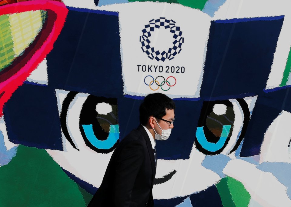Maskot tokijské olympiády Miraitowa (obrázek na pozadí) roušku nepotřebuje, koronavirus na něj nemůže. Japonci takové štěstí nemají. A jejich nadšení pro olympiádu tváří v tvář pandemii bledne. Foto: Kim Kjonghun, Reuters