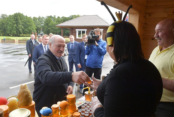 Běloruský prezident Alexandr Lukašenko si zakládá na svém lidovém vystupování a projevu. Tentokrát si připíjí s producentkou medu v kostýmu včelky. Zdroj: president.gov.by