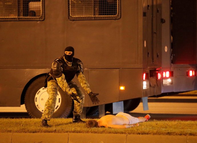Příslušník speciálních běloruských jednotek OMON nad tělem muže, kterého srazilo v noci na pondělí v centru Minsku policejní vozidlo. Foto: Reuters / Vasilij Fedosenko