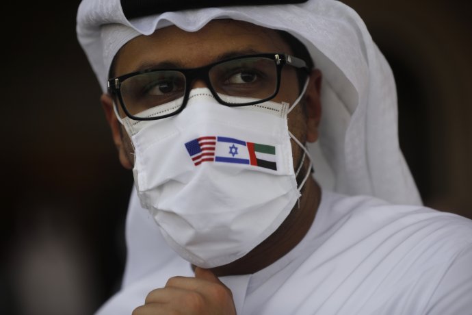 Člověk v tradičním arabském oděvu doplněném izraelskou a americkou vlajkou není na Blízkém východě často k vidění. Navázání leteckého spojení mezi Tel Avivem a Abú Dhabí to změnilo. Foto: ČTK/AP
