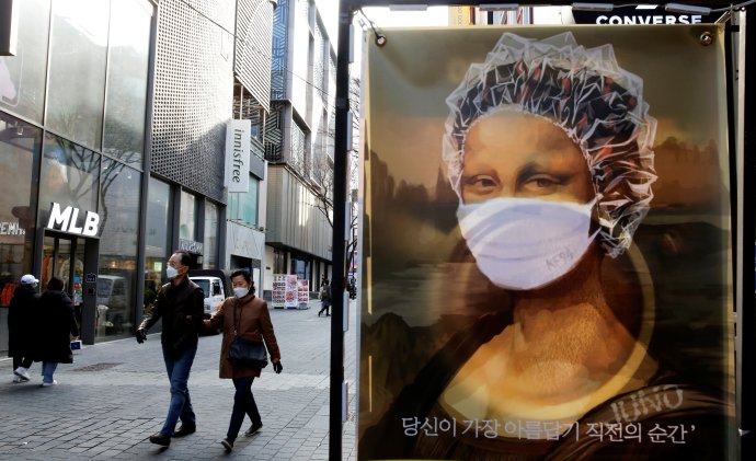 Mona Lisa v roušce a ochranné čepici na plakátu v jihokorejském Soulu (27. listopadu 2020). Foto: Heo Ran, Reuters
