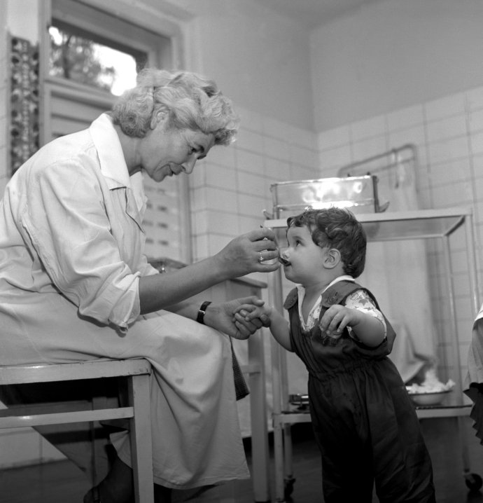 „V týdnu od 27. května do 1. června probíhá na celém území naší republiky druhá etapa očkování proti dětské obrně živou očkovací látkou. Na sn. záběr z dětského zdravotnického střediska v Praze 6-Vokovicích.“ Foto a dobový text z roku 1960: ČTK