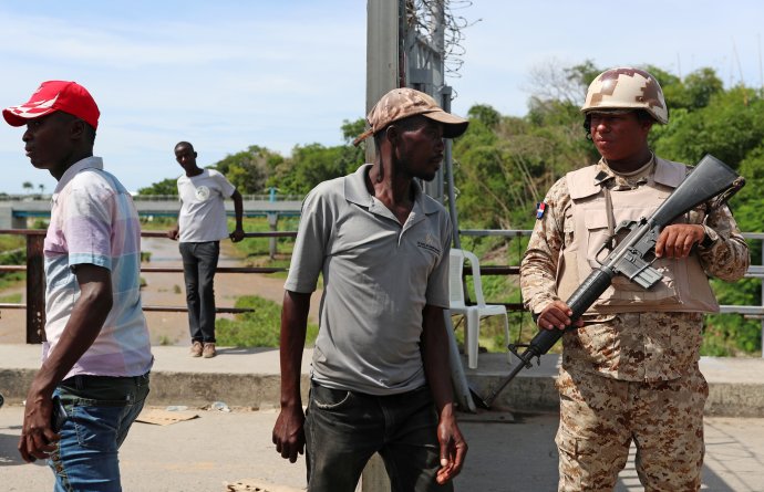 Dominikánský voják s obyvateli Haiti, kteří chtějí přejit hranici. Foto: Ricardo Rojas, Reuters
