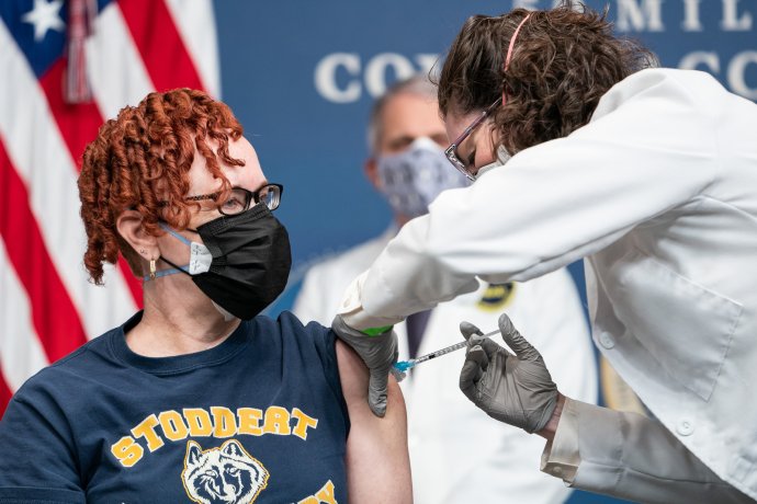 Učitelka ze školy ve Washingtonu Victoria Legerwood-Riverová je očkována v Bílém domě. Za ní přihlíží hlavní epidemiolog Anthony Fauci. Foto: Adam Schultz, Bílý dům