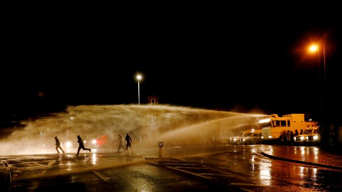 Protestující a policejní vodní dělo při nepokojích na Springfield Road v severoirském Belfastu. Foto: Jason Cairnduff, Reuters