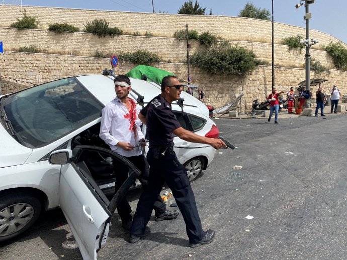Izraelský policista zachraňuje dvoučlennou židovskou posádku auta, kterou u Lví brány u jeruzalémského Starého Města kamením napadli palestinští mladíci. Muži v autě mezitím v nastalé vyhrocené situaci na chodníku porazili několik Palestinců. Foto: Ilan Rosenberg, Reuters