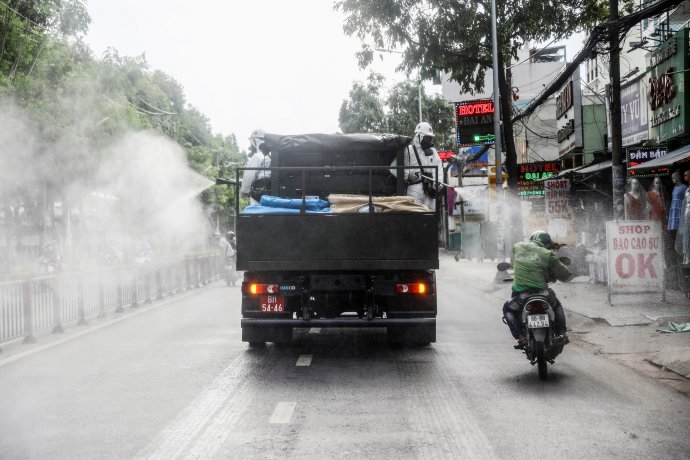 Dezinfekční četa za propuknutí nové vlny koronavirové infekce ve vietnamském Ho Či Minově městě nebere ohledy ani na motocyklistu. Foto: Reuters