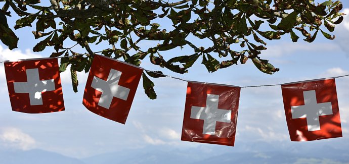 Vlajky s helvétským křížem, kam se člověk podívá. To je 1. srpen v zemi uprostřed Alp. Foto: Adobe Stock