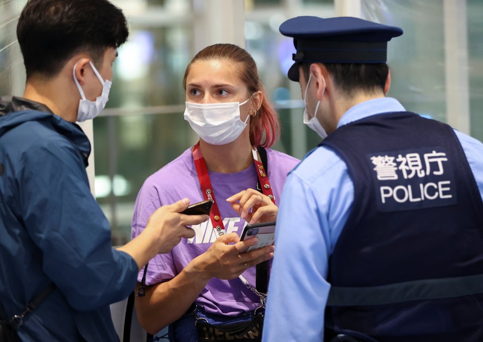 Běloruská atletka Kryscina Cimanouskaja diskutuje s policisty na tokijském letišti. Foto: Reuters