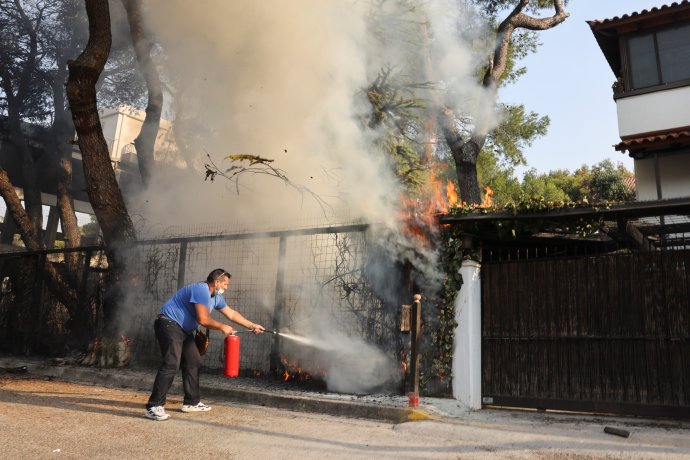 Muž se snaží hasicím přístrojem uhasit požár u domů na athénském předměstí Varympompi. Foto: Giorgos Moutafis, Reuters