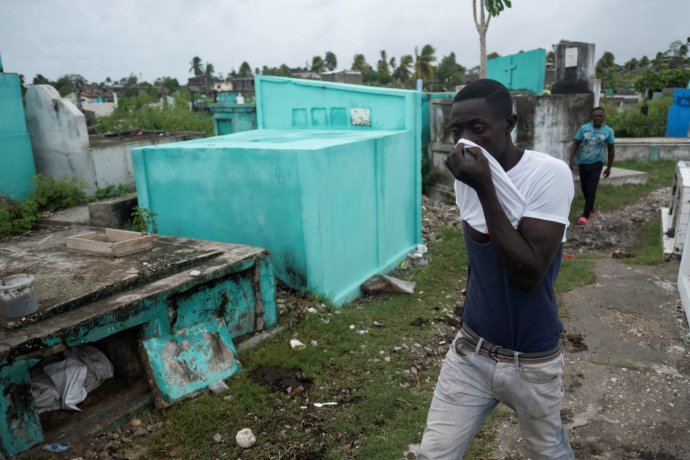 Oběti zemětřesení na Haiti: muž ve městě Les Cayes si zakrývá obličej, když míjí otevřený hrob. Foto: Ricardo Arduengo, Reuters