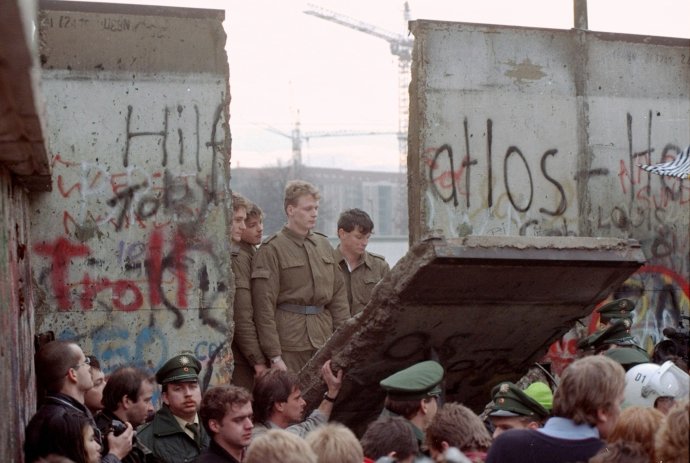 Jedenáctého listopadu 1989 prolomili demonstranti první průlez Berlínskou zdí. Východoněmecké vojáky, kteří měli do té doby rozkaz střílet na každého, kdo se k ní jen přiblíží, nastalá situace poněkud překvapila. ČTK / AP / Lionel Cironneau