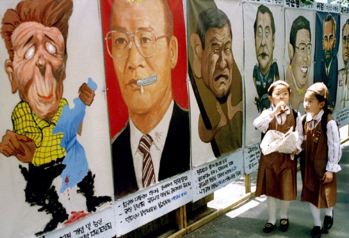Karikatury v ulicích jihokorejského Kwangdžu na archivním snímku ze 17. května 1995 - den před výročím tzv. události 518 neboli vojenského masakru prodemokratického hnutí v Kwangdžu v květnu 1980. Čon Tuhwana (v brýlích) a další vůdce tehdejší diktatury doplňuje Ronald Reagan. Američané o chystané akci spojeneckého Čonova režimu věděli. Foto: Reuters