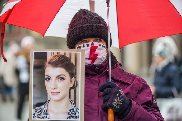 Třicetiletá Izabela (na portrétu) zemřela letos v září v nemocnici v šestém měsíci těhotenství na septický šok. Protestující žena, která její fotografii drží, má na roušce červený blesk – symbol iniciativy Strajk kobiet, Stávka žen. Foto: Michal Fludra, NurPhoto via Reuters