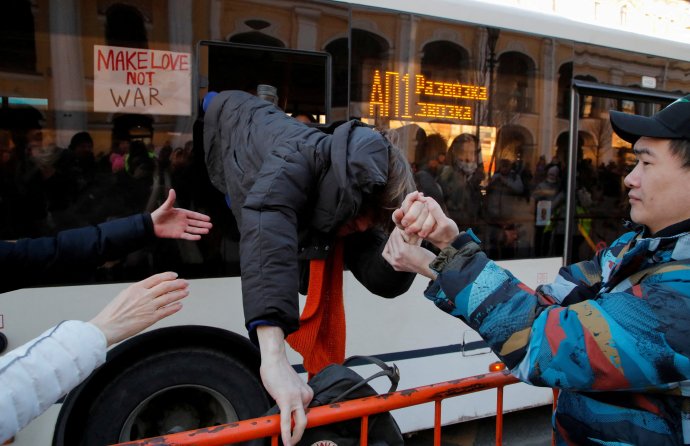 Petrohrad, neděle 27. února. Zadržený demonstrant proti ruské invazi na Ukrajinu prchá za pomoci dalších z okna autobusu, jímž policie sváží zadržené protestující na stanici. Proti válce se protestovalo nejméně v 53 městech a k dnešnímu ránu bylo zadrženo bezmála 2800 Rusů. Foto: Anton Vaganov, Reuters