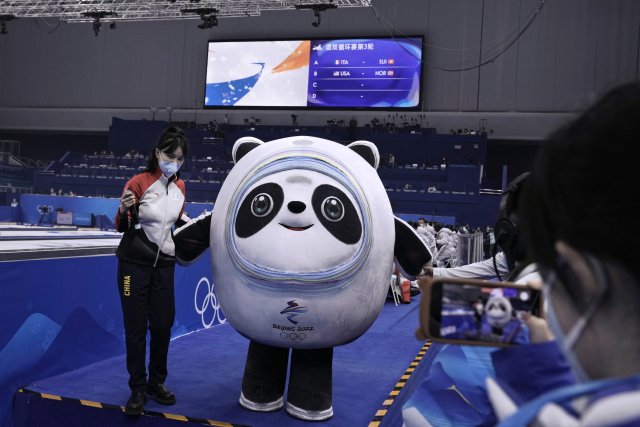 Dobrovolníci se v curlingové hale fotí s maskotem olympiády v Pekingu, jenž nese jméno Ping Tun-tun (Bing Dwen Dwen). Foto: Nariman El-Mofty, AP/ČTK