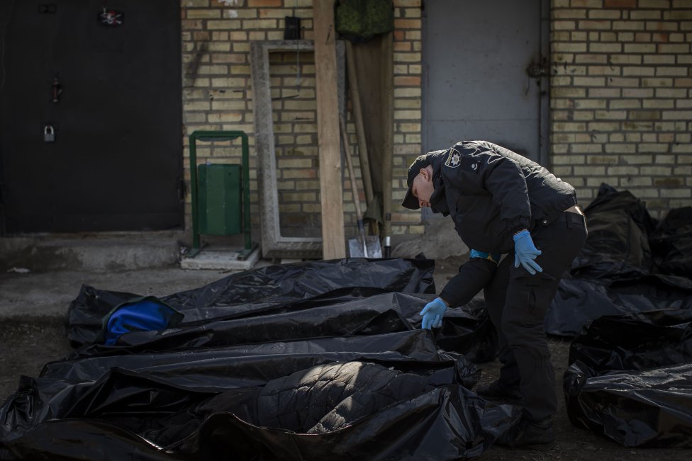 Ukrajinský policista prohlíží mrtvé tělo. Foto: Gabriel Kuchta, Deník N