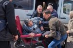 Volunteers help a man in wheelchairs from a minibus who was evacuated from the Donetsk region. He will stay with his family overnight at Good News Church (Dobraya Vest') and leave the next day to the west of Ukraine by train.
