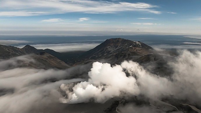 Po Kurilských ostrovech už pár století baží jak Japonci, tak Rusové. Na snímku je sopka Ebeko na ostrově Paramušir, zahalená v mlžných oblacích - jedna z teorií, které vysvětlují původ názvu Kurily, praví, že jméno pochází z ainského slova kur neboli mrak, stín. Foto: Alexandpilat, Wikimedia CC BY 4.0