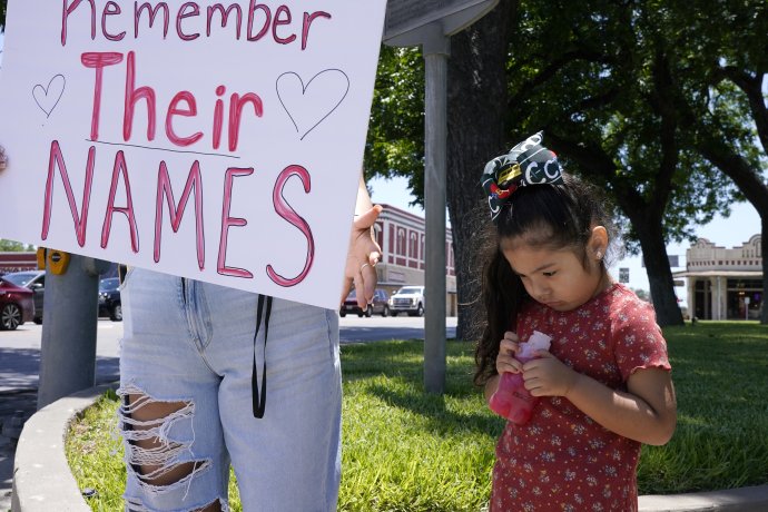 Žena s nápisem „Nezapomeňme jejich jména“ a holčička s hračkou v ruce uctívají památku 21 obětí střelce, který zabíjel v texaském městě Uvalde. Foto: John Lamparski, Reuters