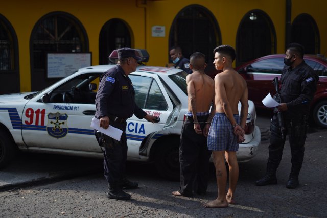 Dva muži podezřelí z členství v násilném gangu jsou odváděni policií v Salvadoru. Prezident tam kvůli zabíjení gangů vyhlásil stav pohotovosti a prodloužil ho o další měsíc. Foto: Víctor Peña, DPA/ČTK