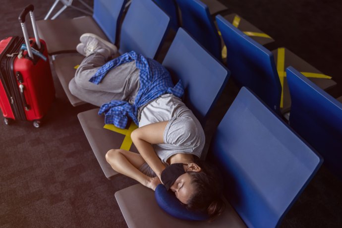 Žena spící na sedáčkách v odletové hale letiště. Ilustrační foto: SpiceCat, Adobe Stock
