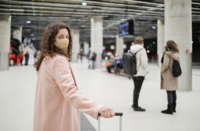 Žena na autobusovém nádraží, stále s rouškou. Foto: Halfpoint, Adobe Stock