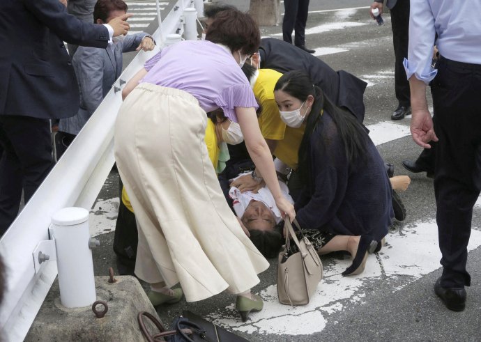 Postřelený Šinzó Abe leží na chodníku v západojaponském městě Nara. Atentátník ho zasáhl, když Abe vystupoval během předvolební kampaně k volbám do horní komory parlamentu, které se v Japonsku konají tuto neděli. Foto: Kjódó via Reuters