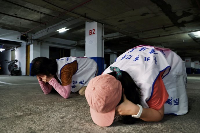 Tchajwanci při branném cvičení ukazují, jak se chovat v krytu. Obyvatelstvo opakovaně nacvičuje chování pro případ vojenského útoku z komunistické Číny. Toto je 22. červenec 2022 v Tchaj-peji. Foto: Ann Wangová, Reuters