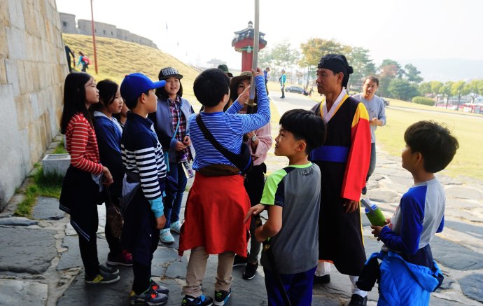 Školní výlet na pevnost Hwasong, památku UNESCO asi 30 km od Soulu. Spokojení školáci zkoumají meč "strážce pevnosti" (vpravo), uprostřed dohlíží učitelka. Děti jsou nadšené - možnost uniknout z mnohdy dusivých čtyř stěn školní třídy je vždy vítaná. Foto: Magdalena Slezáková, Deník N