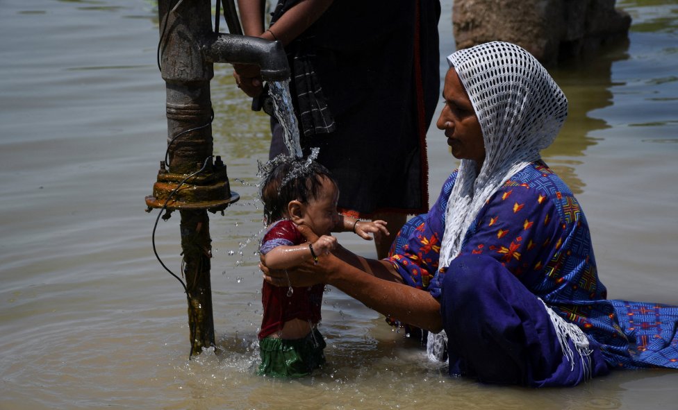 Kalná povodňová voda hrozí samým nebezpečím: choroboplodnými zárodky, ostrými předměty, jedovatými hady. Matka se v nejpostiženější provincii Sindh snaží vykoupat své malé dítě pod čistou vodou z pumpy - potíž je, že ani ta nemusí být bezpečná. Foto: Jásir Radžput, Reuters