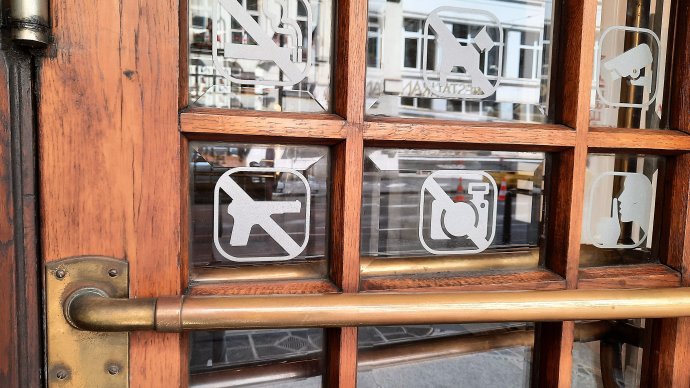 Piktogram s přeškrtnutou pistolí na dveřích banky. Platnost i vymahatelnost jsou diskutabilní. Foto: Jan Moláček, Deník N