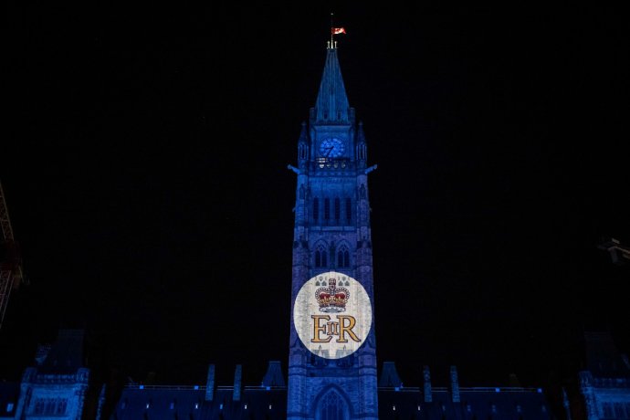 Budova parlamentu v hlavním městě Ottawě se v den úmrtí britské královny zahalila do fialového světla a fasádu osvítila královská šifra. Foto: Justin Tang / Zuma Press / Profimedia