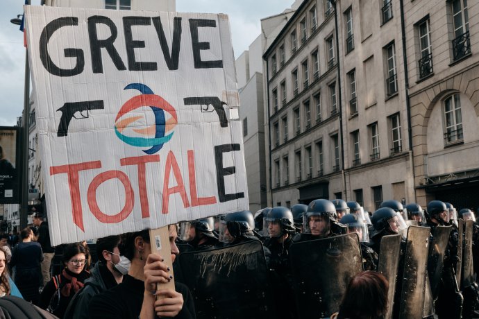 Nedělní demonstrace v pařížských ulicích proti zdražování nákladů na živobytí a nečinnosti v otázce klimatu. Logo společnosti TotalEnergies odkazuje na stávkující na rafineriích. Na transparentu tak stojí "totální stávka". Zdroj: Benoit Durand, Hans Lucas / Reuters