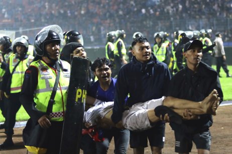 Policisté po násilných střetech v Indonésii odnášejí zraněného fanouška. Foto: ČTK, AP