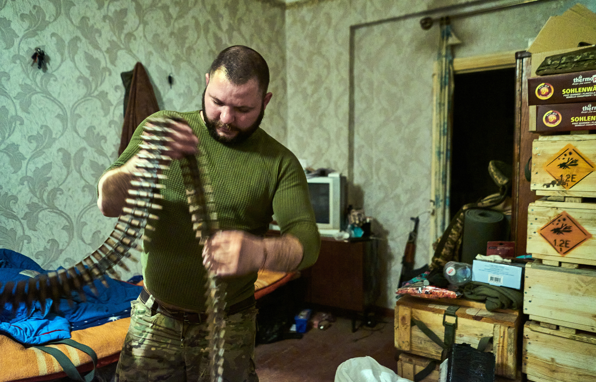 Sasha called also Bear from the 28th Intelligent Company of the Knights of the Winter getting ready machine gun belt for their position on frontline.