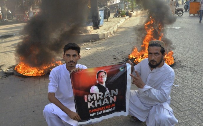Dvojice mužů v pákistánském Hyderábádu nenechává nikoho na pochybách, že stojí za zatčeným a z korupce obviněným expremiérem Chánem. Za nimi hoří zapálené pneumatiky a dým stoupá i z mnoha jiných míst napříč zemí. V Péšávaru podpálili protestující dokonce i budovu Pákistánského rozhlasu, v Láhauru si z hořícího domu odnesli pávy. Foto: Pervéz Masih, AP via ČTK