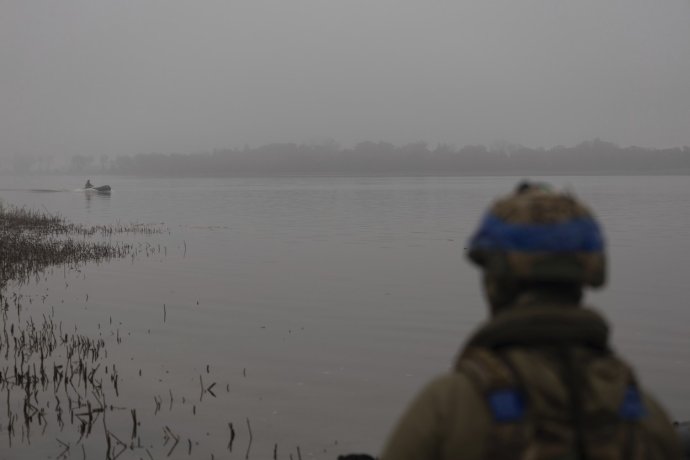 Ukrajinský voják se dívá na svého kolegu, který se plaví na člunu po řece Dněpr na frontové linii u Chersonu. Foto: Alex Babenko / AP / ČTK